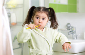 Child little girl brushing teeth in bath