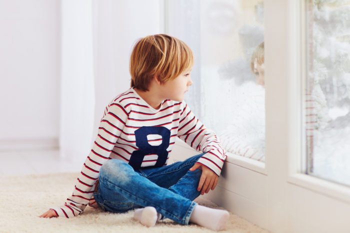 Niño sentado mirando por la ventana