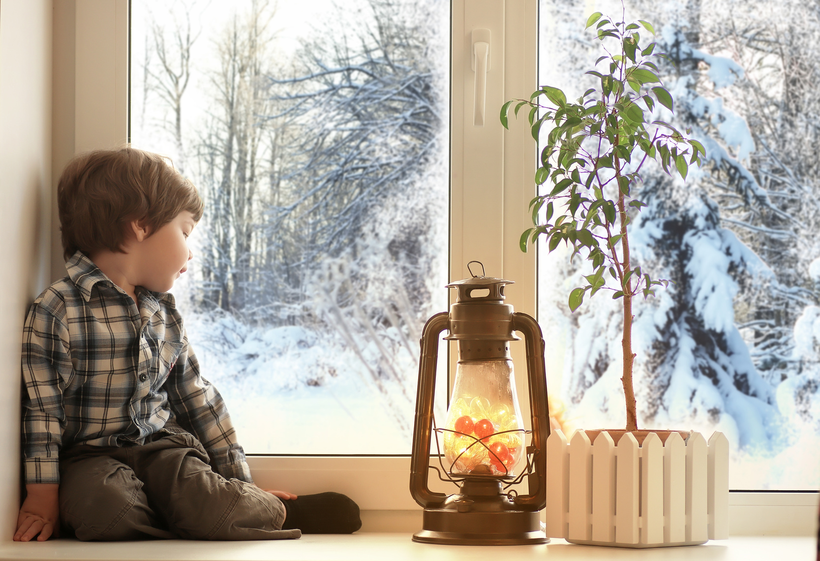 Niño sentado al lado de una ventana